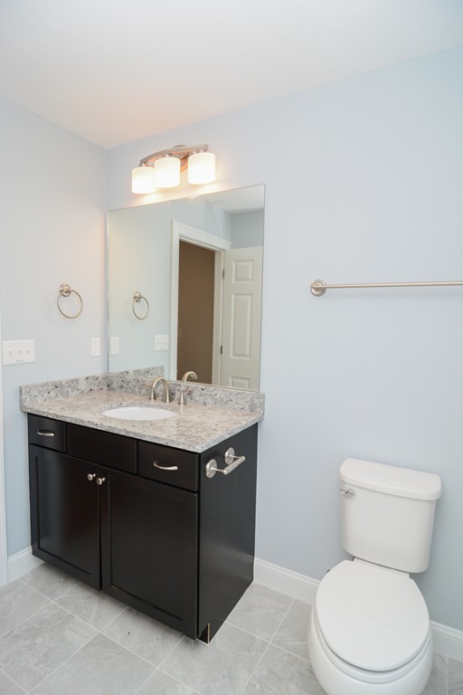 1400 Gorham Street, Unit 40 Lowell, MA 01852 - Photo 18 of 19 a bathroom with a granite countertop toilet sink and mirror