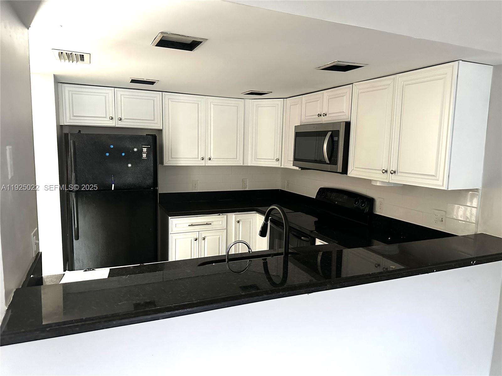 4220 Southwest 71st Terrace Davie, FL 33314 - Photo 11 of 16 a kitchen with a refrigerator a stove and white cabinets