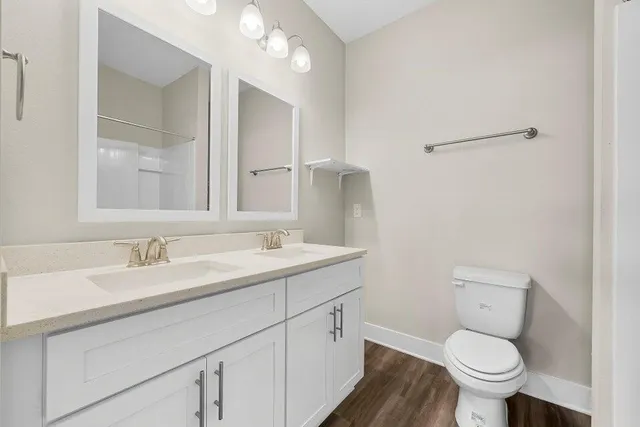 a bathroom with a granite countertop toilet a sink and a mirror