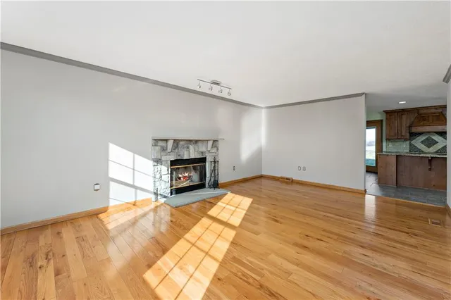 a view of empty room with fireplace and wooden floor