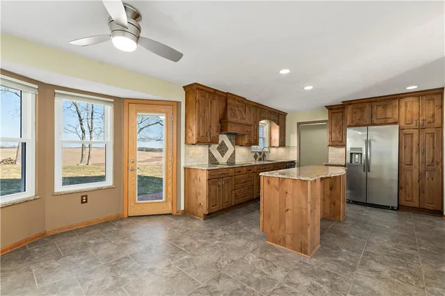 a kitchen with stainless steel appliances granite countertop a refrigerator a oven a sink with island and large windows