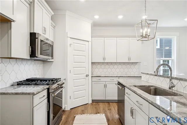 a kitchen with stainless steel appliances granite countertop a sink stove a refrigerator and cabinets with wooden floor