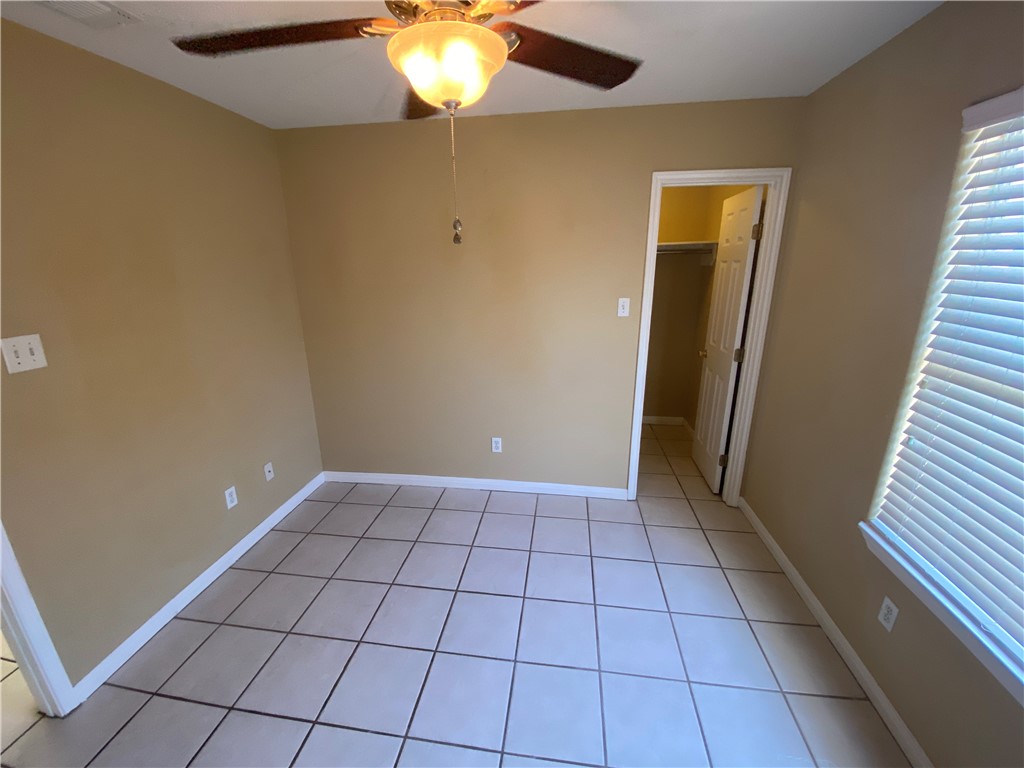 15410 Cruiser Street, Unit B Corpus Christi, TX 78418 - Photo 14 of 25 en empty room with windows and chandelier fan