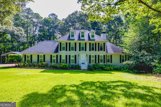a view of a big house with a big yard and potted plants and large trees