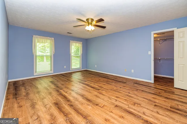 an empty room with windows and ceiling fan