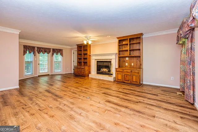 a view of an empty room with wooden floor and fan