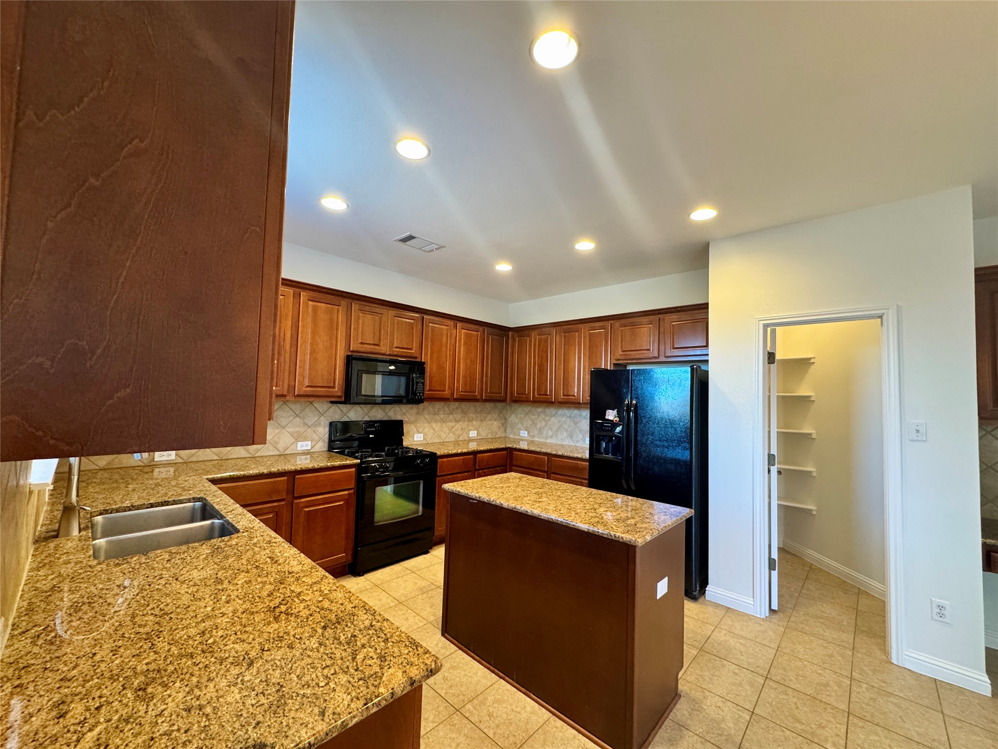3640 Fossilwood Way Round Rock, TX 78681 - Photo 9 of 19 Kitchen with black appliances, a center island, light stone countertops, tasteful backsplash, and recessed lighting