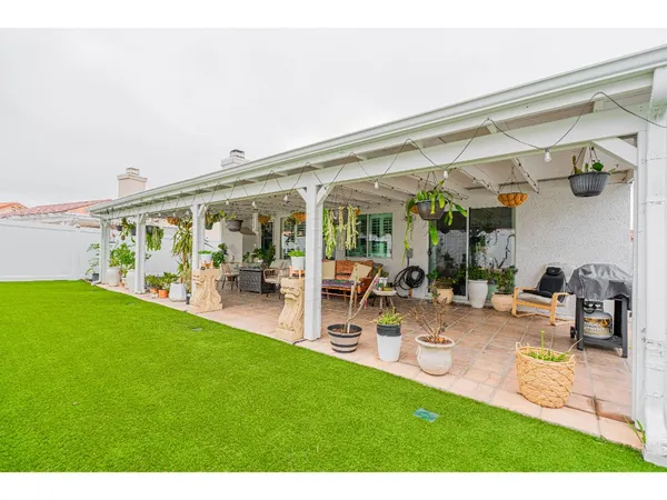 a view of a patio with table and chairs potted plants and floor to ceiling window