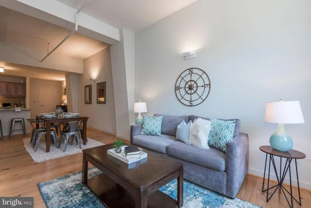 a living room with furniture a rug a lamp and a window