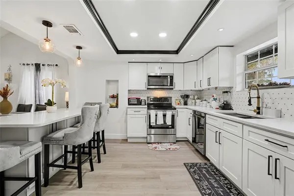 a kitchen with granite countertop a sink stainless steel appliances and white cabinets