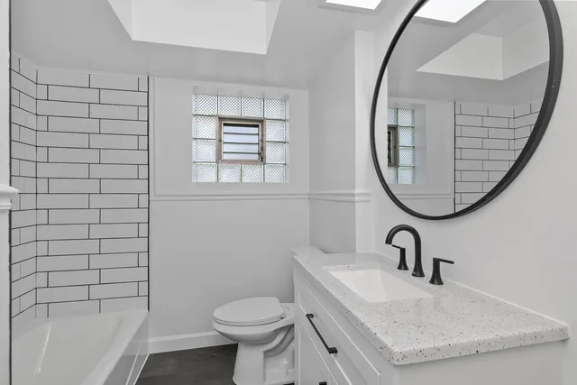 a bathroom with a sink a toilet and a mirror