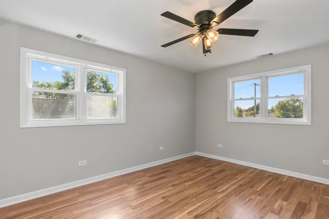 a view of an empty room with window and wooden floor