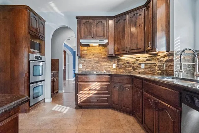 a kitchen with granite countertop a refrigerator and a sink