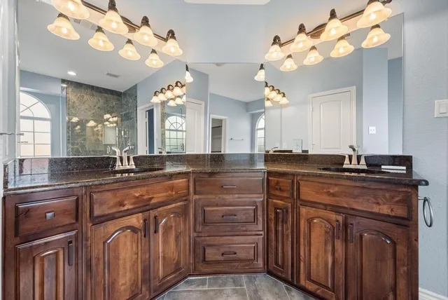 a spacious bathroom with a granite countertop sink a large mirror and a chandelier