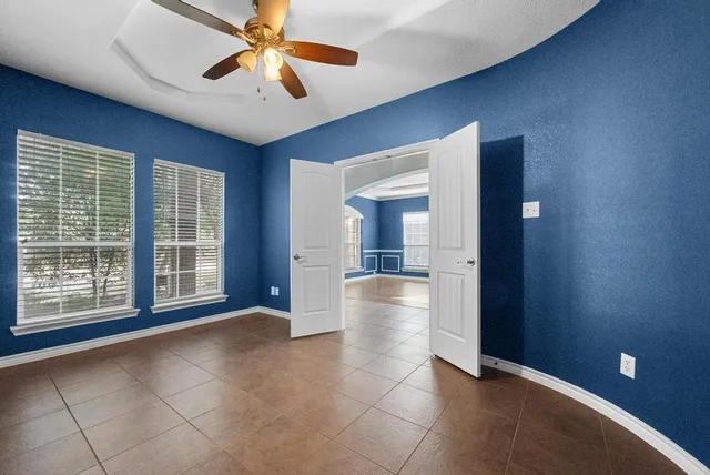 a view of an empty room with window and chandelier fan