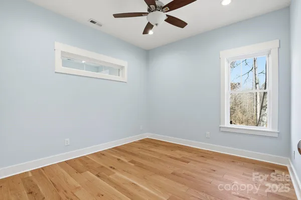 a view of a big room with wooden floor and windows