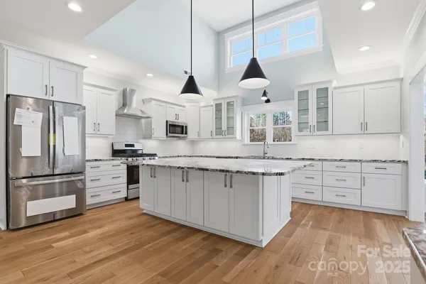 a kitchen with stainless steel appliances granite countertop a stove a sink and white cabinets