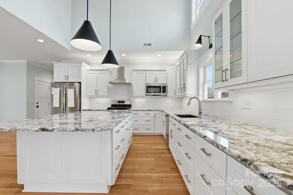 a large kitchen with stainless steel appliances granite countertop a sink and cabinets
