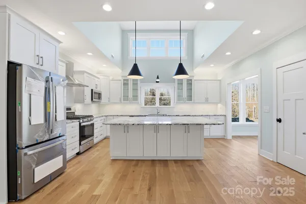 a large kitchen with stainless steel appliances kitchen island granite countertop a large stove a refrigerator a oven and a wooden cabinets with wooden floor