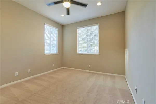 an empty room with chandelier fan and windows