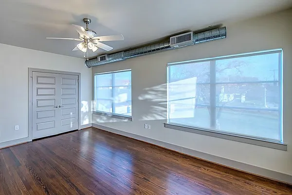 a view of an empty room with wooden floor and a window