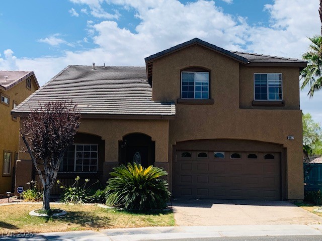 View of front of home with stucco siding, driveway, and a garage