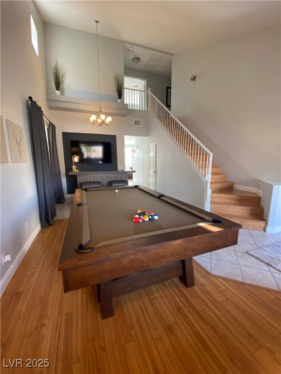 10637 Amblewood Avenue Las Vegas, NV 89144 - Photo 19 of 32 Rec room with a towering ceiling, billiards table, light wood-style flooring, healthy amount of natural light, and a chandelier
