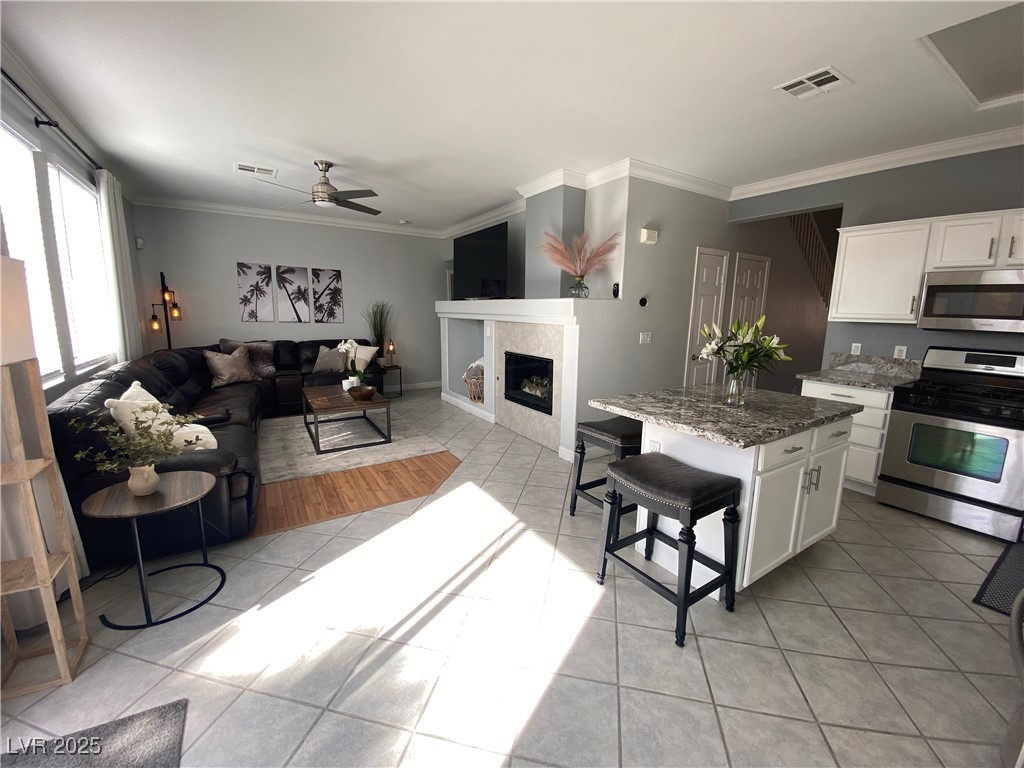 10637 Amblewood Avenue Las Vegas, NV 89144 - Photo 31 of 32 Kitchen with ornamental molding, stainless steel appliances, open floor plan, a breakfast bar area, and white cabinetry
