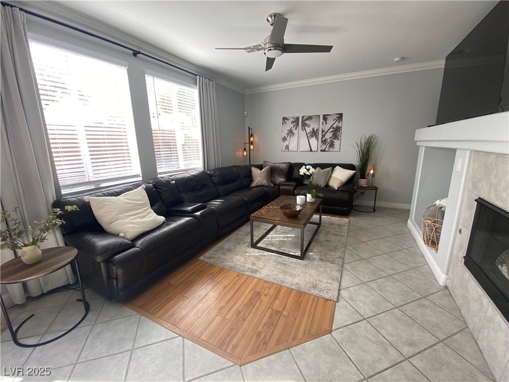 10637 Amblewood Avenue Las Vegas, NV 89144 - Photo 24 of 32 Living area with light tile patterned flooring, ornamental molding, a tile fireplace, and a ceiling fan