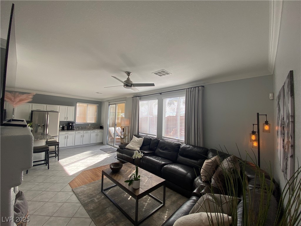 10637 Amblewood Avenue Las Vegas, NV 89144 - Photo 25 of 32 Living area featuring ornamental molding, light tile patterned floors, and a ceiling fan