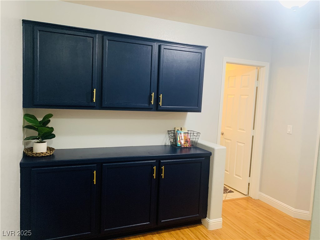 10637 Amblewood Avenue Las Vegas, NV 89144 - Photo 6 of 32 Bar area featuring dark countertops, light wood finished floors, and blue cabinetry