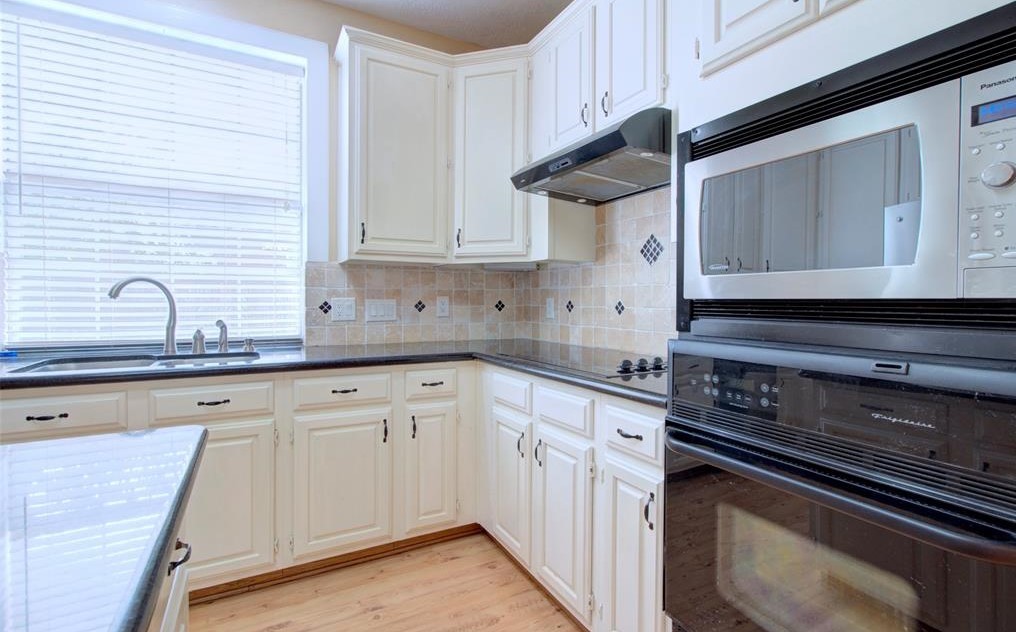 1226 Rabbs Crossing Sugar Land, TX 77479 - Photo 19 of 50 a kitchen with granite countertop white cabinets and black appliances