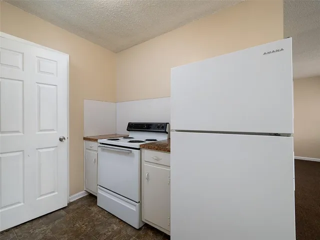 a white refrigerator freezer and a stove sitting inside of a kitchen