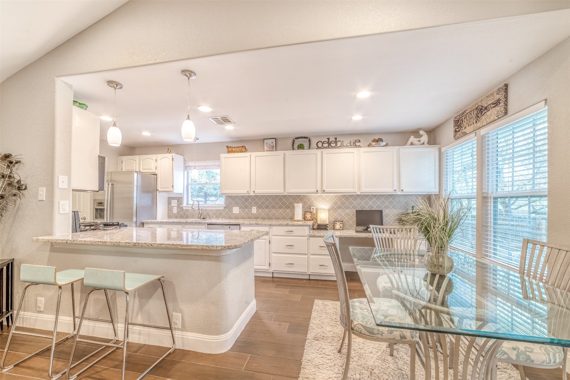 a kitchen with stainless steel appliances kitchen island granite countertop a table and chairs in it