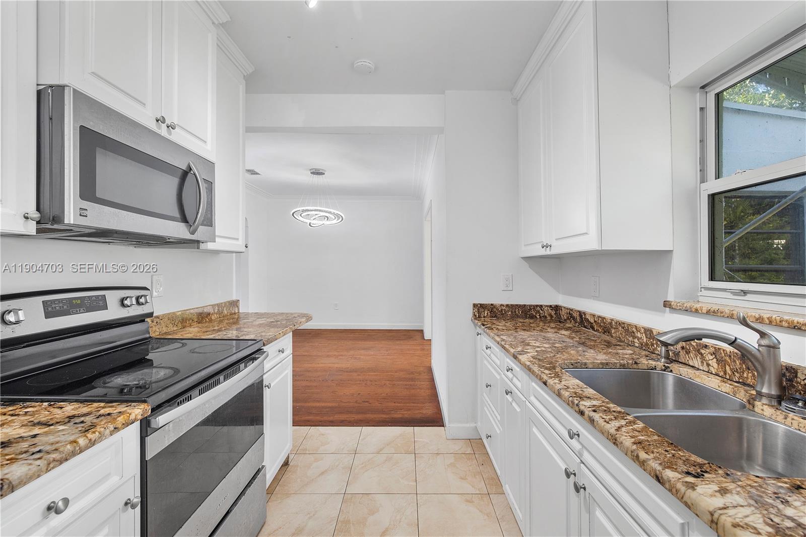 8826 Emerson Avenue Surfside, FL 33154 - Photo 12 of 25 a kitchen with granite countertop a sink stainless steel appliances and cabinets