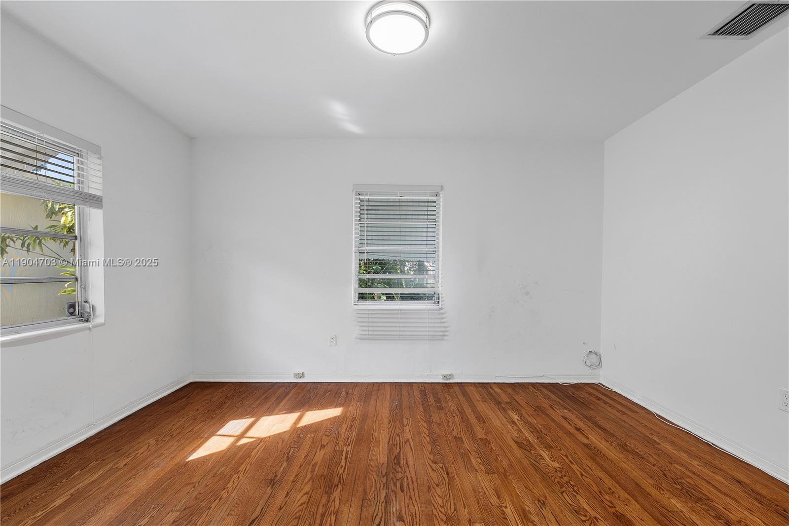 8826 Emerson Avenue Surfside, FL 33154 - Photo 13 of 25 an empty room with wooden floor and windows