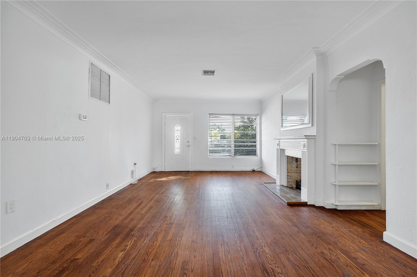 8826 Emerson Avenue Surfside, FL 33154 - Photo 9 of 25 an empty room with wooden floor fireplace and windows
