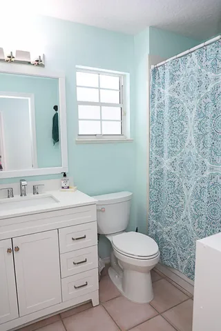 a bathroom with a toilet a sink a mirror a window and vanity