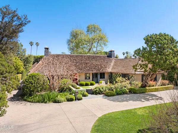 a front view of a house with a yard and potted plants