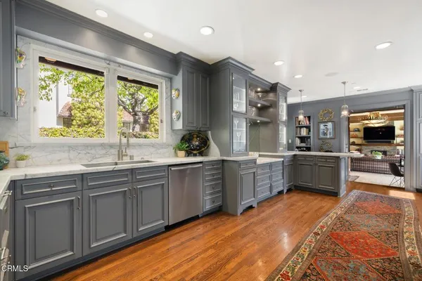 a kitchen with stainless steel appliances granite countertop sink window and white cabinets