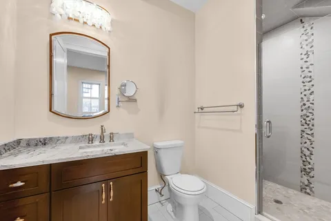 a bathroom with a toilet a sink a mirror and shower