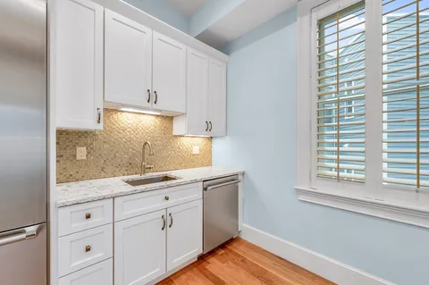 a kitchen with granite countertop white cabinets and a window