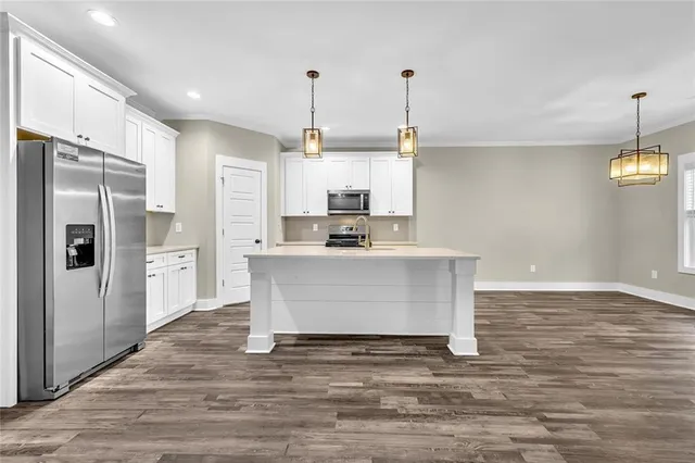 a view of kitchen with stainless steel appliances granite countertop a stove a refrigerator a sink and white cabinets