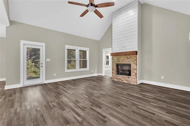 a view of an empty room with wooden floor fireplace and a window