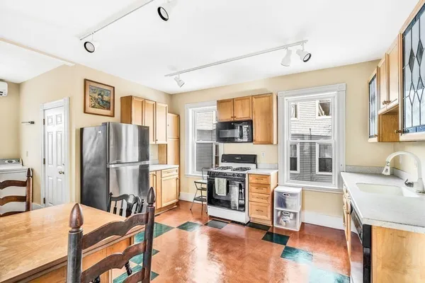 a view of a kitchen with furniture a refrigerator and wooden floor