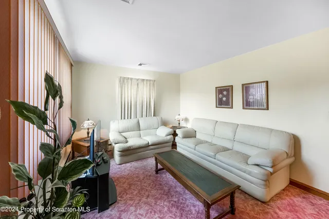a living room with furniture a flat screen tv and a potted plant