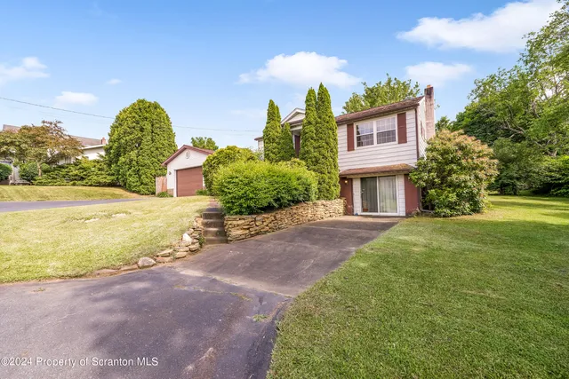 a front view of a house with garden and trees