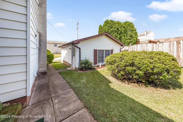 a view of a house with a yard plants and large tree