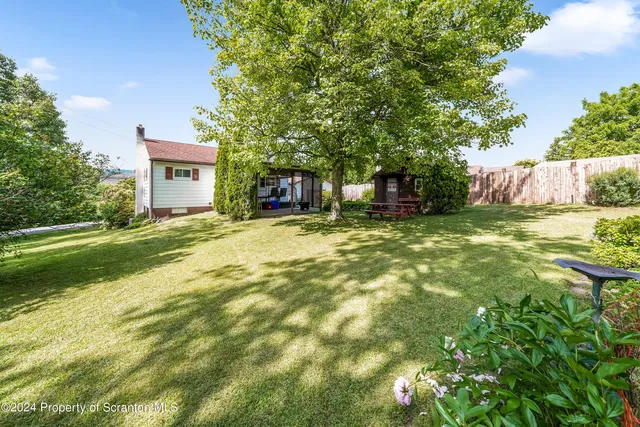 a view of a house with a big yard and a large tree