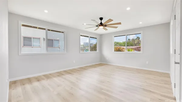 a view of empty room with wooden floor and fan